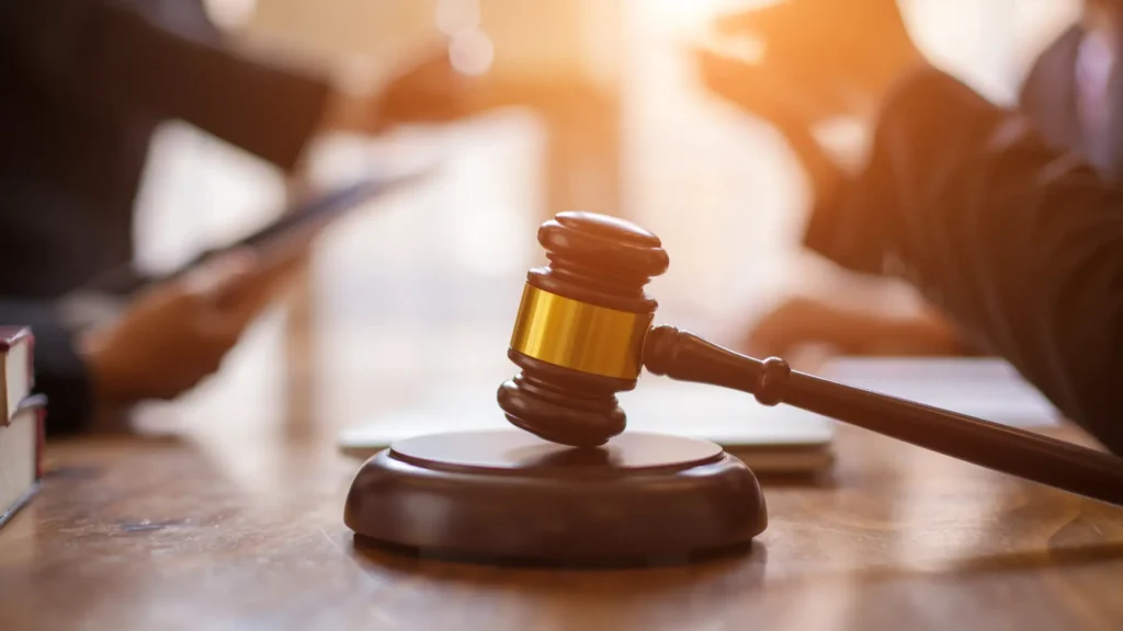 תמונת אווירה של מפגש סביב שולחן עורך דין פלילי. על השולחן מונח פטיש שופטים (פטיש יושב ראש) וספרי משפט.